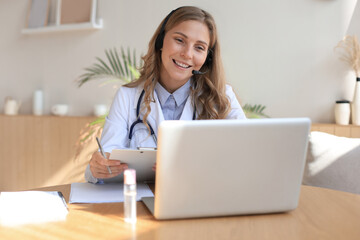 Concentrated doctor working online with a laptop sitting in a desk in a consultation.