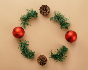Wall Mural - christmas and new year round frame with red balls and pine cone on beige background top view with co