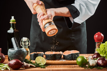 Chef using pepper grinder to season raw trout steaks