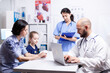 © DC Studio - Doctor writing treatment on laptop during consultation of child and mother in hospital office. Healthcare physician specialist in medicine providing health care services treatment examination.