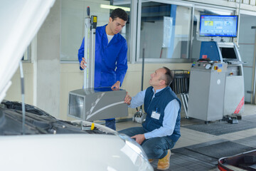 two mechanics working on a car