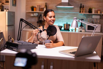 Wall Mural - Social media analyst speaking on microphone during podcast with neon light in the background, recording. Online show On-air production internet broadcast host streaming live content.