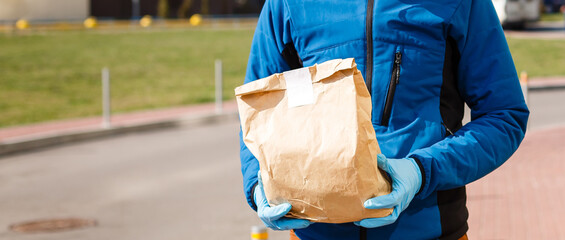 Wall Mural - Delivery man holding paper bag with food, food delivery man in protective mask