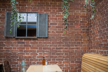 Window on a red bricks wall with a table and wooden seats at the bottom