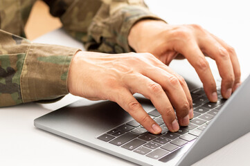Closeup shot of a unrecognizable military person typing on a laptop keyboard