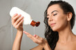© New Africa - Beautiful young woman with bottle of shampoo in shower at home