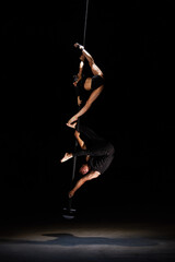 Wall Mural - Man and woman doing exercises on pylon isolated on black background.Pole dance concept.