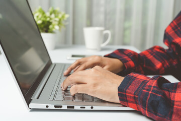 Close up. hands woman typing keyboard on laptop at house. Student searching data for research, and learning online in office concept.