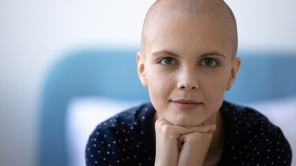 Head shot portrait close up hairless young woman struggling with cancer, oncology disease, strong female patient looking at camera, dreaming about recovery, healthcare and treatment concept