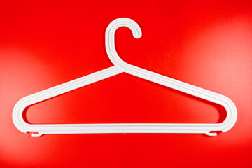 Canvas Print - Plastic white coat hanger clothes hanger on red background.