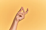 Fototapeta  - Arm and hand of caucasian man over yellow isolated background snapping fingers for success, easy and click symbol gesture with hand