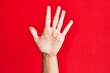 © Krakenimages.com - Arm of caucasian white young man over red isolated background counting number 5 showing five fingers