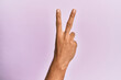 © Krakenimages.com - Arm and hand of caucasian young man over pink isolated background counting number 2 showing two fingers, gesturing victory and winner symbol