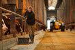 © Seventyfour - Full length portrait of young woman cleaning cow shed while working at farm or family ranch, copy space