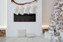Fireplace With Christmas Stockings And Gifts In Interior Of Room. White Fireplace Is Decorated With Christmas Socks In Living Room. Empty Stockings Hung On Fireplace On Xmas. Scandinavian Interior	