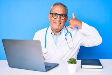 Sticker - Senior handsome man with gray hair wearing doctor uniform working using computer laptop smiling doing phone gesture with hand and fingers like talking on the telephone. communicating concepts.