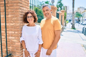 Poster - Middle age couple smiling happy leaning on the wall at street of city.