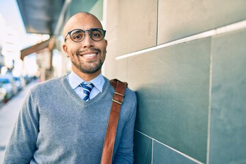 Young african american businessman smiling happy leaning on the wall at the city.