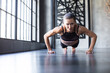 Athletic woman doing push-ups on the floor in a modern gym loft. Working out.