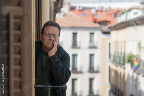 lifestyle portrait of sad and depressed mature man 65 to 70 years old at home balcony feeling lonely and confused facing getting old and retirement alone looking away thoughtful