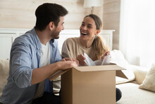 Joyful Unboxing. Overjoyed Laughing Millennial Husband And Wife New Owners Renters Tenants Of House Apartment Unpacking After Relocation Moving, Happy Young Spouses Receiving Awaited Postal Delivery