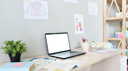 Table with white blank mock up computer screen for online virtual social distance remote learning. School child home desk interior with books and laptop mockup monitor for elearning ads concept.
