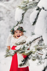 Portrait of a woman in a red jacket in a cold winter forest. Girl with a wreath on her head in a snow-covered winter forest