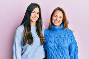 Canvas Print - Hispanic family of mother and daughter wearing wool winter sweater with a happy and cool smile on face. lucky person.