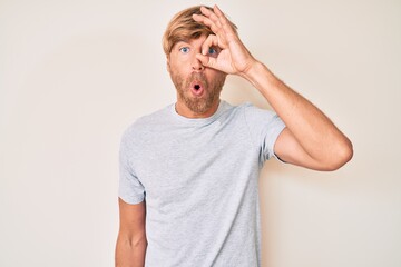 Sticker - Young blond man wearing casual clothes doing ok gesture shocked with surprised face, eye looking through fingers. unbelieving expression.