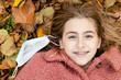 © Edwin - Smiling teenage girl with braces laying in autumn leaves