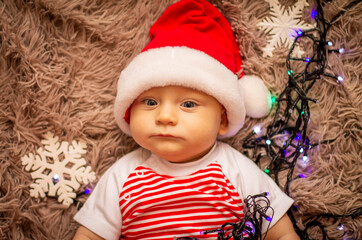 Wall Mural - the kid wishes everyone a happy new year wearing a santa claus hat.