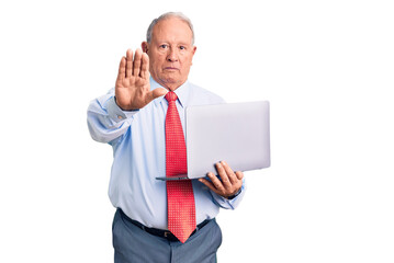 Wall Mural - Senior handsome grey-haired man wearing tie using laptop with open hand doing stop sign with serious and confident expression, defense gesture