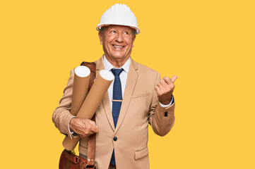 Sticker - Senior caucasian man wearing safety helmet holding blueprints pointing thumb up to the side smiling happy with open mouth