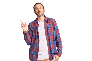 Young handsome man wearing casual clothes with a big smile on face, pointing with hand finger to the side looking at the camera.