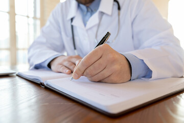  Doctor handwriting. Close up view of male physician surgeon general practitioner hand filling paper forms and medical journals after accepting patients, making records to cards and treatment profiles
