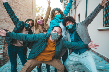 Wall Mural - Happy friends walking on city street - New normal concept with young people having fun together covered by face masks