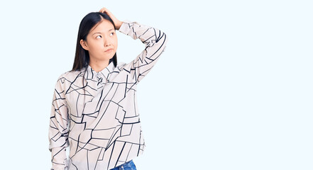 Sticker - Young beautiful chinese woman wearing casual shirt confuse and wondering about question. uncertain with doubt, thinking with hand on head. pensive concept.