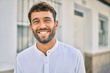 Wall Mural - Handsome man with beard wearing casual white shirt on a sunny day smiling happy outdoors