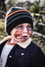 A Three Year Old Boy Dresses Up As A Zombie For Halloween Posing On A Rural Road In Ontario Canada At Sunset.  A Spooky Apocalyptic Scene.