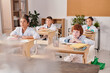 © pressmaster - Several schoolkids in whitecoats listening to what their teacher talking about