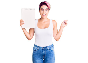 Sticker - Young beautiful woman with pink hair holding notebook smiling happy pointing with hand and finger to the side