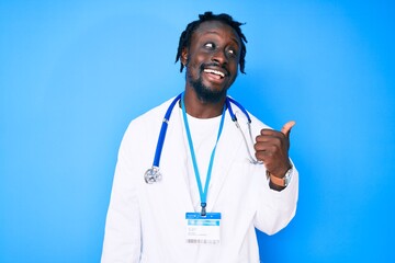 Poster - Young african american man with braids wearing doctor stethoscope and id pass smiling with happy face looking and pointing to the side with thumb up.