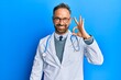 © Krakenimages.com - Handsome middle age man wearing doctor uniform and stethoscope smiling positive doing ok sign with hand and fingers. successful expression.