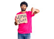 © Krakenimages.com - Handsome young man with curly hair and bear holding woman power banner with angry face, negative sign showing dislike with thumbs down, rejection concept