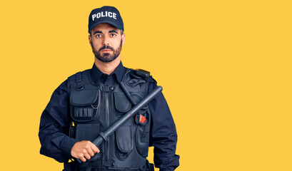 Poster - Young hispanic man wearing police uniform holding baton thinking attitude and sober expression looking self confident