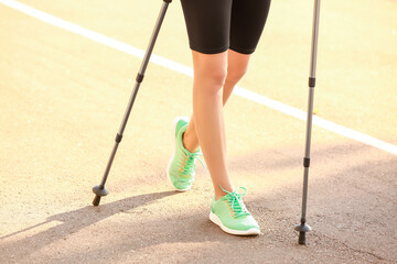 Young woman training with walking poles outdoors