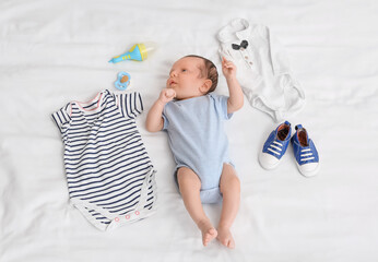 Sticker - Cute little baby with clothes and accessories lying on bed, top view