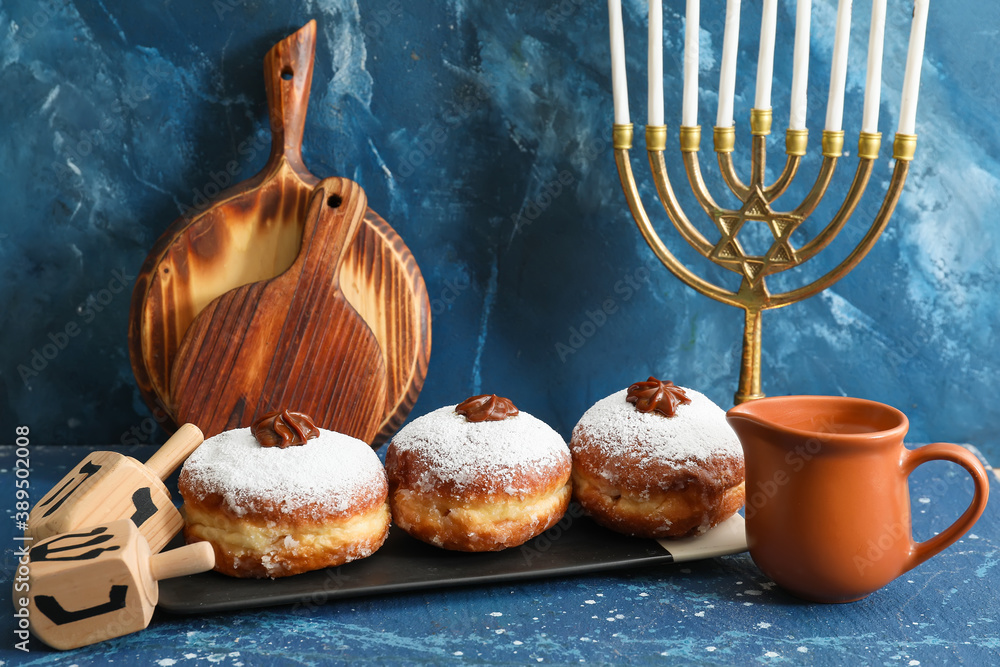 Menorah, dreidels and donuts for Hanukkah on color background