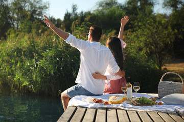 Wall Mural - Happy couple spending time on pier at picnic, back view