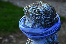 Moss Covered Stone Statue Head In Ancient Greek Or Roman Style With Bandana Scarf On Her Mouth As A Face Mask As Symbol Of COVID 19 Protection Or Silencing.